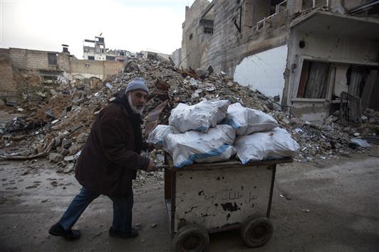 سوري يدفع عربة مليئة بأكياس الحطب في دوما إحدى ضواحي دمشق أمس الأول (أ ب أ)