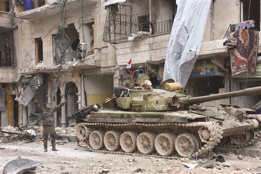 عناصر من الجيش السوري يرفعون علامة النصر بالقرب من دبابتهم في حي السكري في حلب يوم الجمعة الماضي (إ ب أ)