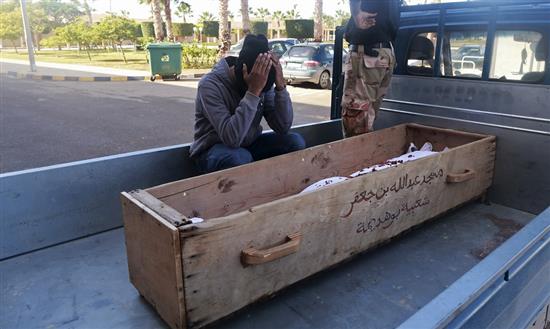 رجل يجلس على جانب جثمان عسكري قتل أمس في معارك بنغازي (رويترز)