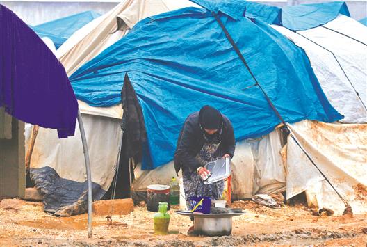 امرأة تنظف أواني الطعام أمام خيمتها في مخيم أعزاز للنازحين السوريين امس (رويترز)
