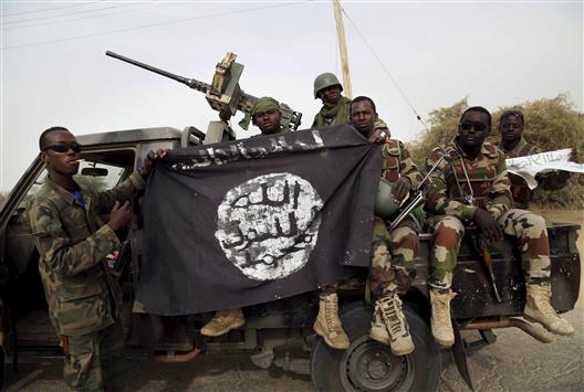 جنود نيجيريون يحملون راية "داعش" بعدما حرروا بلدة من "بوكو حرام" أمس (رويترز)