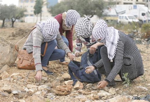فلسطينيات يجمعن الحجارة لرشق قوات الاحتلال الإسرائيلي قرب مستوطنة «بيت إيل» في الضفة الغربية المحتلة أمس (رويترز)