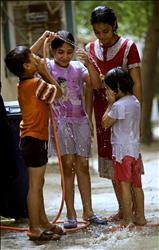 اطفال يلهون بالماء امام منزلهم في الكرادة في بغداد امس حيث وصلت درجة الحرارة الى 43 درجة مئوية.