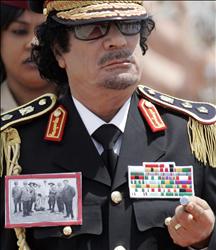 القذافي، وعلى صدره صورة لعمر المختار خلال أسره، لدى وصوله الى روما أمسر.