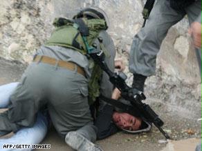 جندي إسرائيلي يقبض على شاب فلسطيني وآخر يراقبه_0