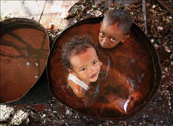 طفلان أندونيسيان »يستحمان« في برميل ماء قذر
