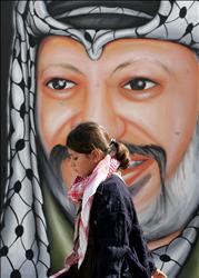 فتاة فلسطينية تمر أمام جدارية تحمل صورة الرئيس الراحل ياسر عرفات في جنين أمس