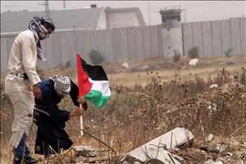 فلسطينيان يغرسان علم فلسطين قرب حاجز «إيريز» الإسرائيلي شمالي قطاع غزة أمس.