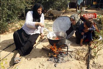 فلسطينيتان تطهوان الطعام على الحطب بسبب النقص الحاد في الوقود نتيجة الحصار على غزة، أمس